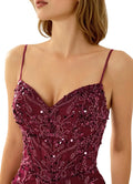Close-up of a person wearing a burgundy sequin dress with thin straps.