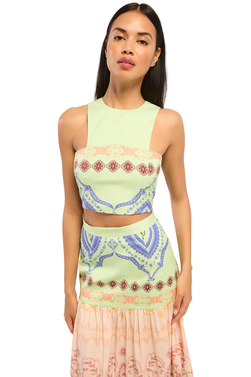 Woman wearing a light green sleeveless top and skirt with intricate patterns on a white background