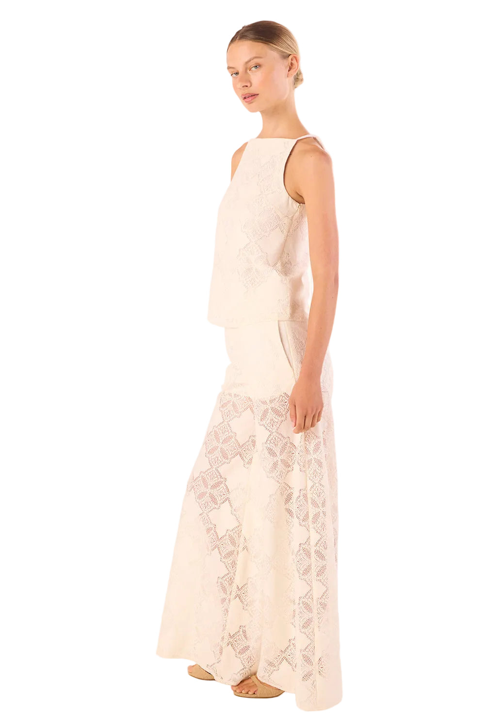 Woman wearing a long, light-colored dress with floral patterns on a white background