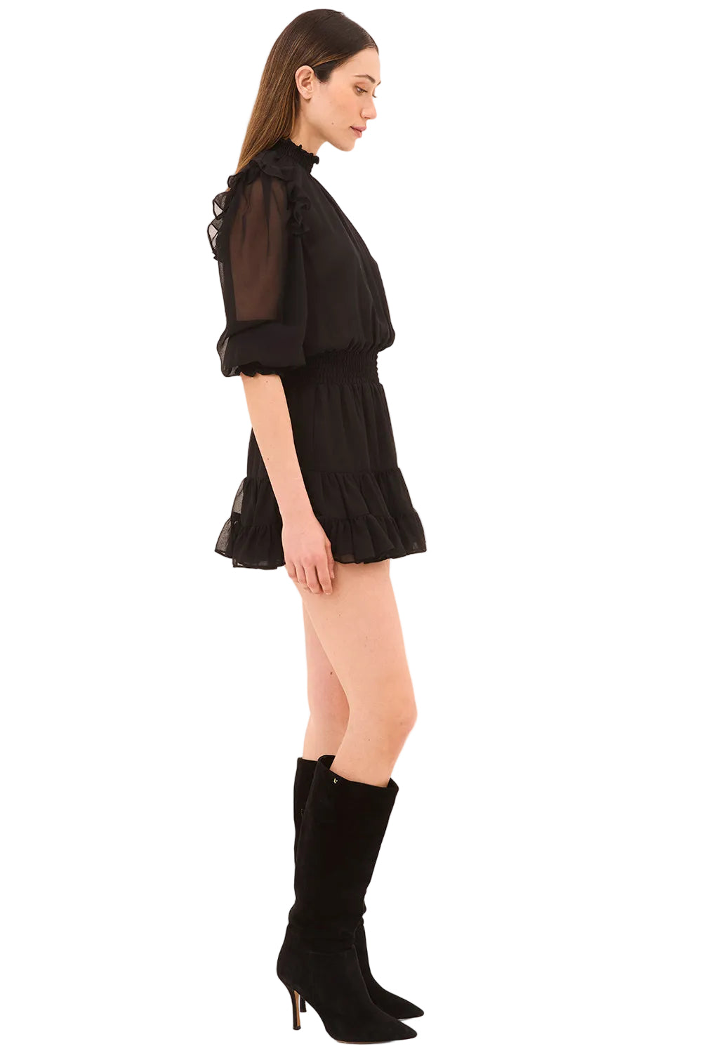 Woman wearing a black outfit with sheer sleeves and high-heeled boots on a beige background