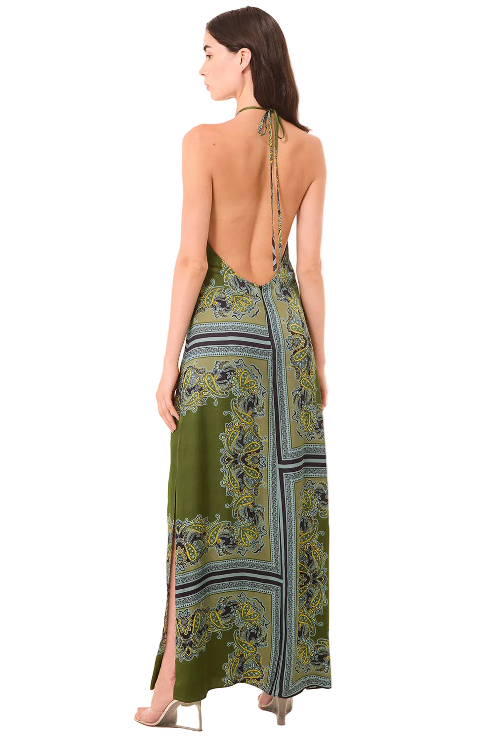 Woman wearing a green patterned dress with open back on a beige background