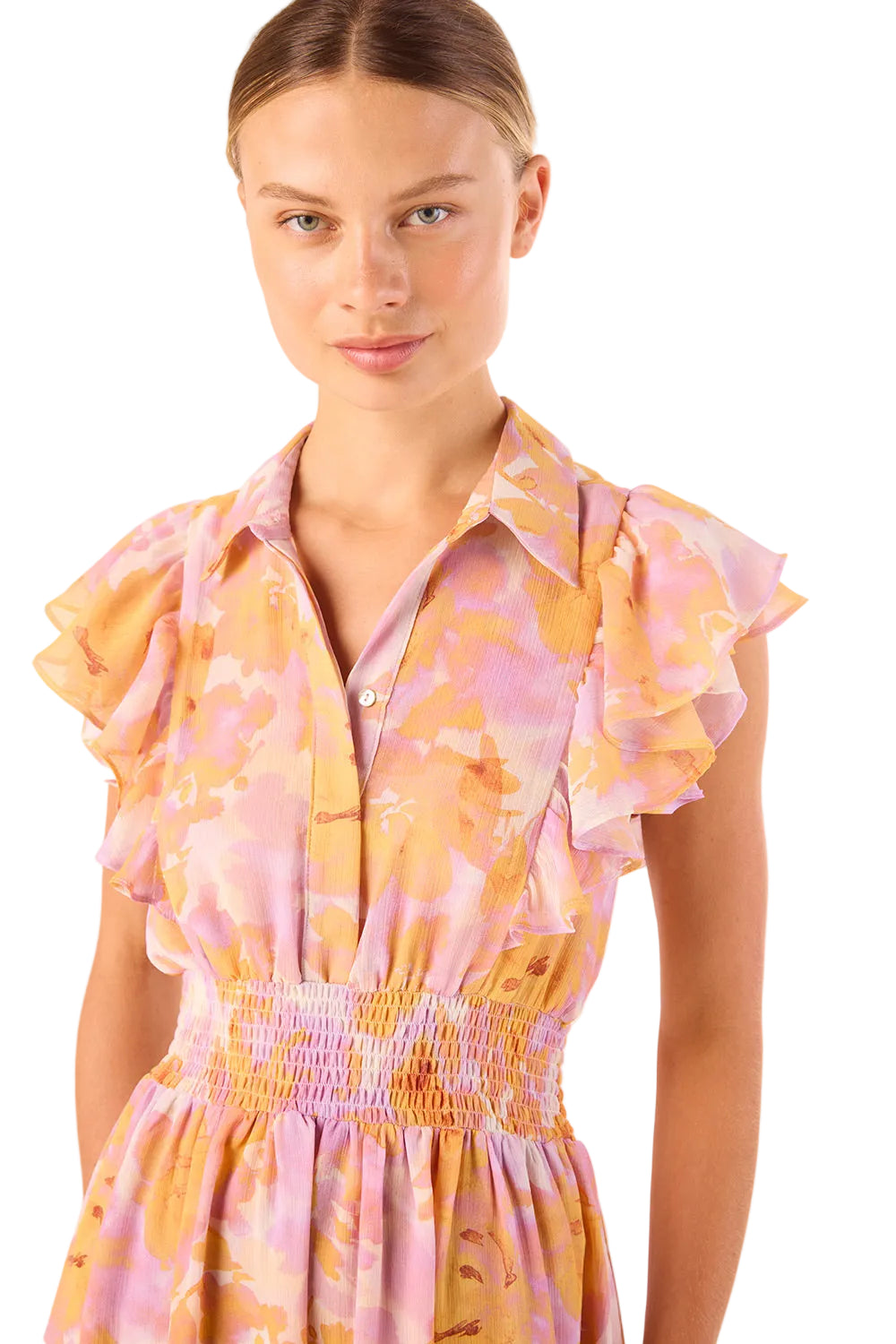 Woman wearing a colorful dress with ruffled sleeves on a plain background